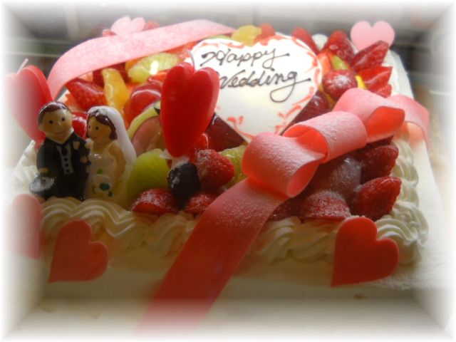 201１年１２月のご注文です。１５名様くらいのサイズのケーキに、ﾌﾙｰﾂたっぷり飾って、大きなリボンと、新郎新婦キャンドルを飾りました。