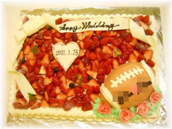 2011年1月のご注文です。60名様用の大きなケーキに、6号サイズのラグビーボールのケーキをのせました。白いリボンを飾って、ぐんとおしゃれになりました。