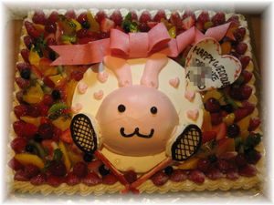 2009年6月のご注文です。30Ｘ４０ｃｍのサイズのフルーツのケーキに、6号サイズで作ったウサギ☆のケーキをのせました。バドミントンのお好きなお二人のために、ラケットをクッキーで作って飾りました！