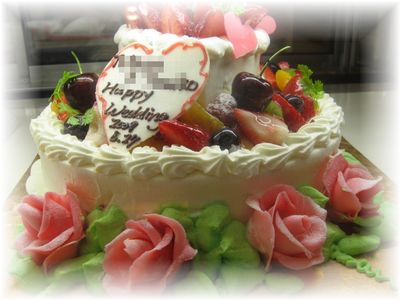 2009年6月のご注文です。8号と、4号の2段のケーキです。ケーキの周りにチョコレートで作ったバラの花を飾りました！グンと豪華になります。下の段には、色とりどりのフルーツを、上の段には、苺系のフルーツを飾っています。