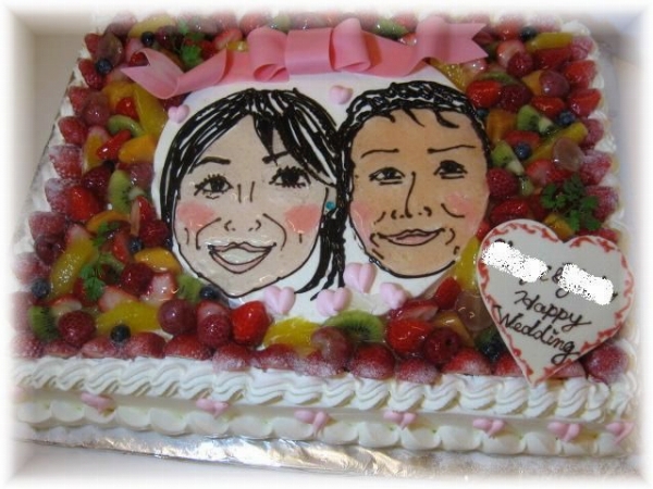 2009年1月のご注文です。ご注文の多い『似顔絵ケーキ』です。フルーツたっぷりのケーキは、４０名様用　。２段目に８号(２４ｃｍ)の薄めのスポンジケーキに、新郎新婦の似顔絵を、チョコレートと、ジャムで描きます。チョコレートで作った大きなりぽんを飾りました。