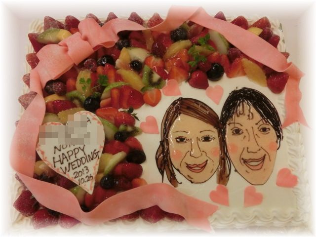 ２０１３年１０月のご注文です。フルーツいっぱいのケーキに、おふたりの似顔絵と大きなリボンを飾りました。