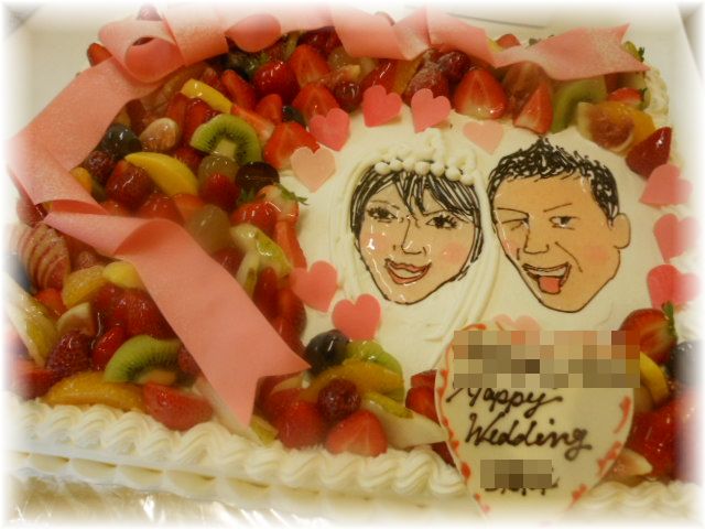 ２０１２年１１月のご注文です。　新郎新婦の似顔絵を書いた大きなケーキに、フルーツと豪華なリボンで華やかに飾りました。